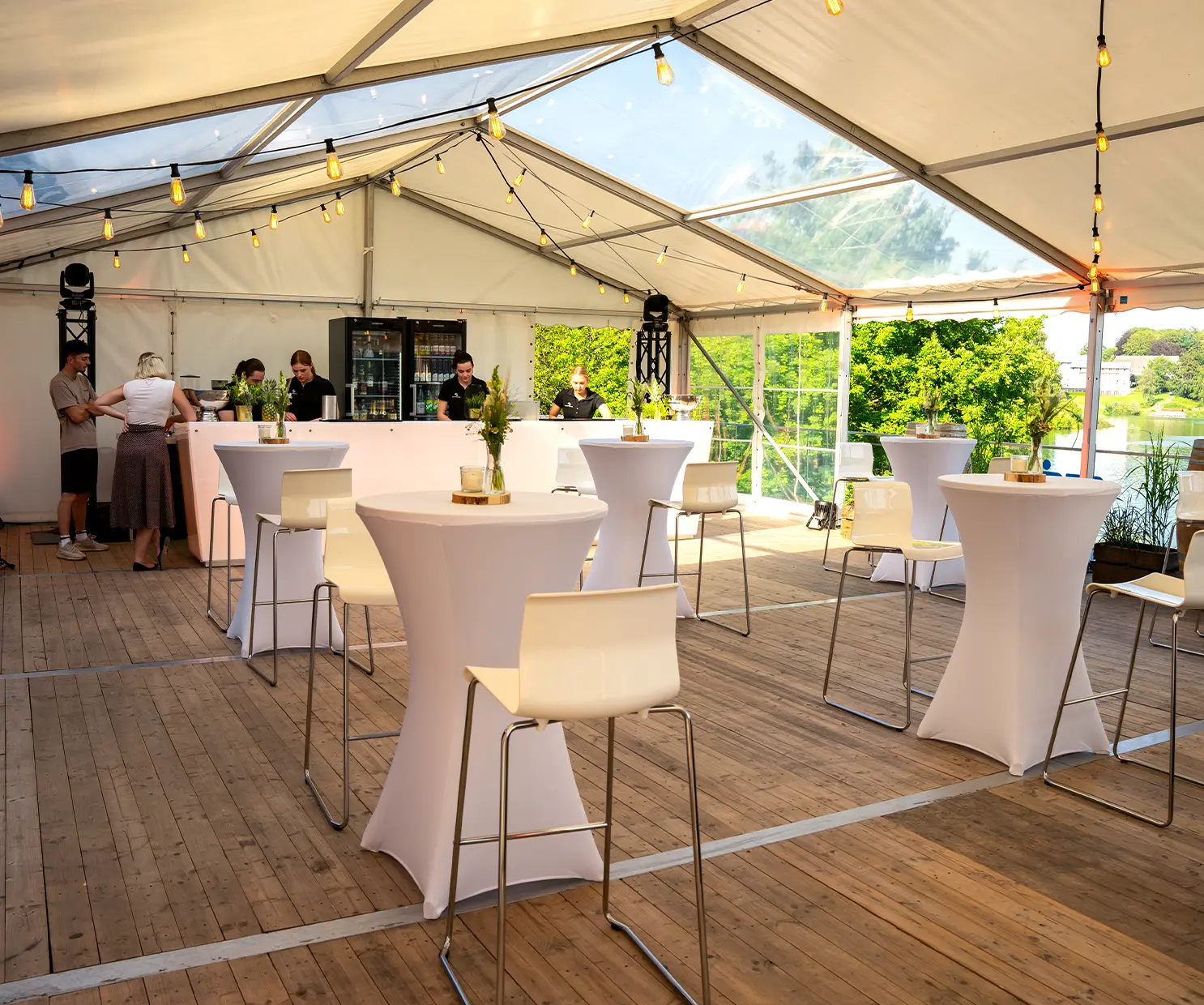 Ein aufgestelltes Zelt mit Holzboden, Theke und Stehtischen
